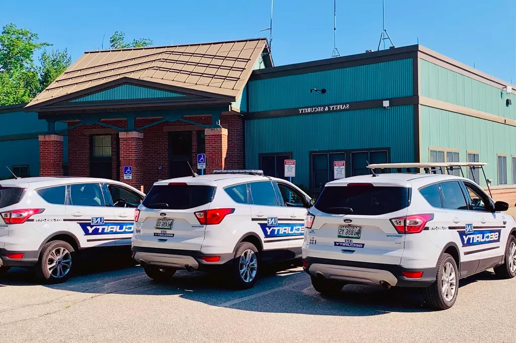 Three U N E security vehicles lined up outside the Safety and Security building