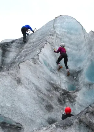 Three U N E students climb the side of a glacier